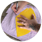 Unfolded party hat being traced over purple fabric