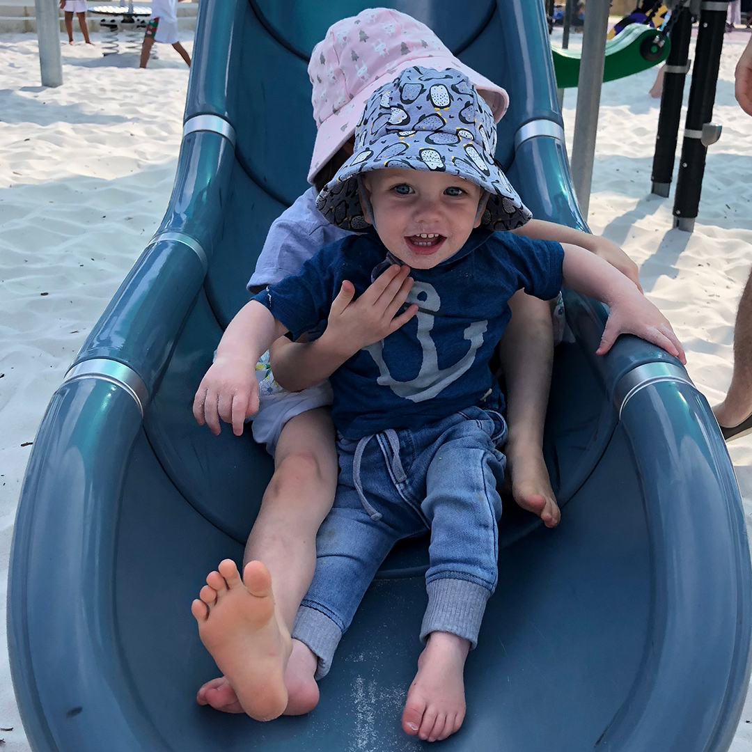 Siblings on slippery dip wearing Bedhead Hats