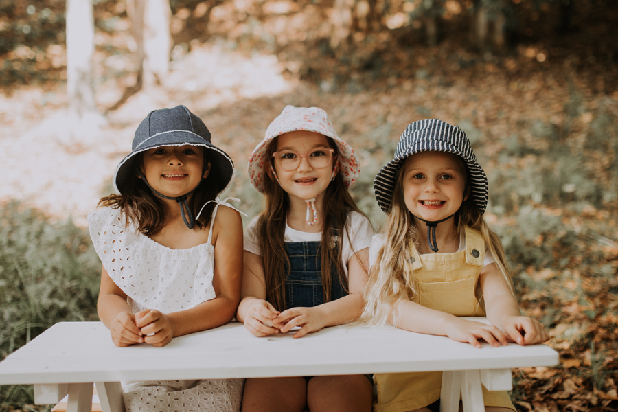 girls in hats outside on table laughing